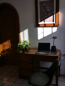 desk with Arabic manuscript and laptop, warm light