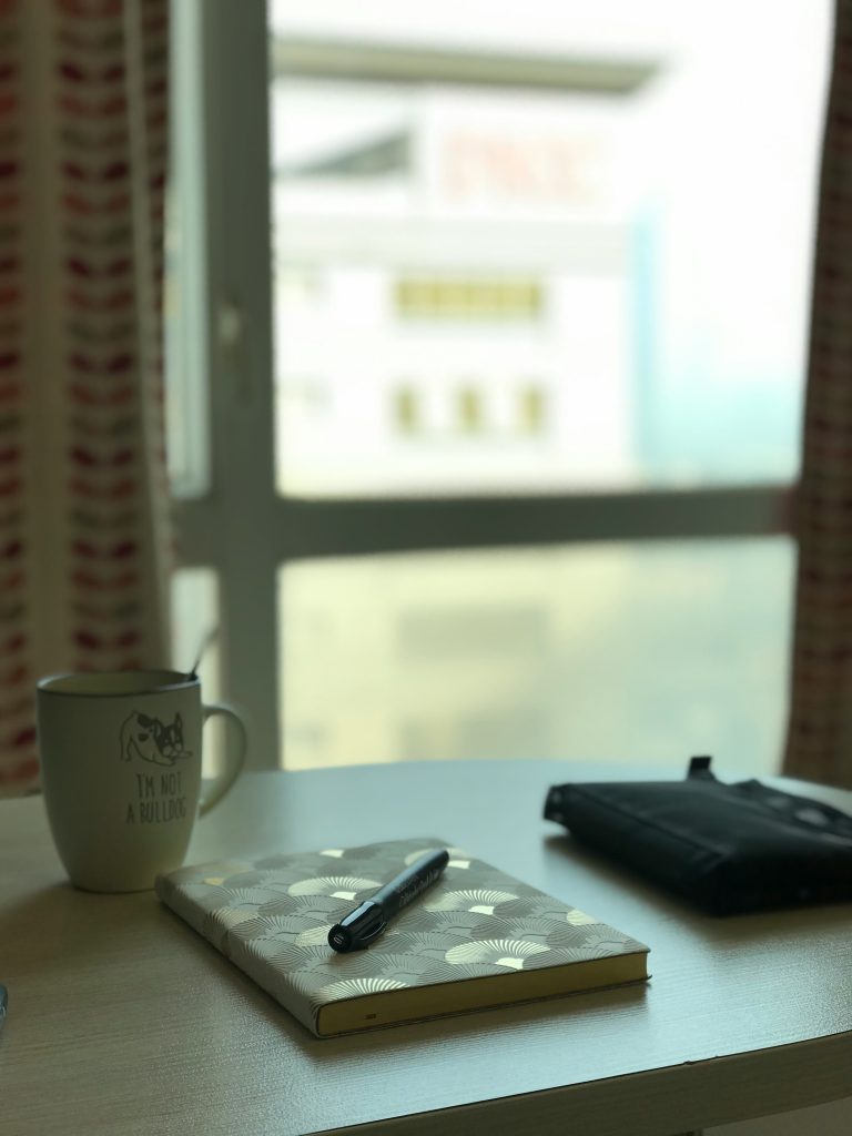 notebook with foreign words handwritten beside coffee cup