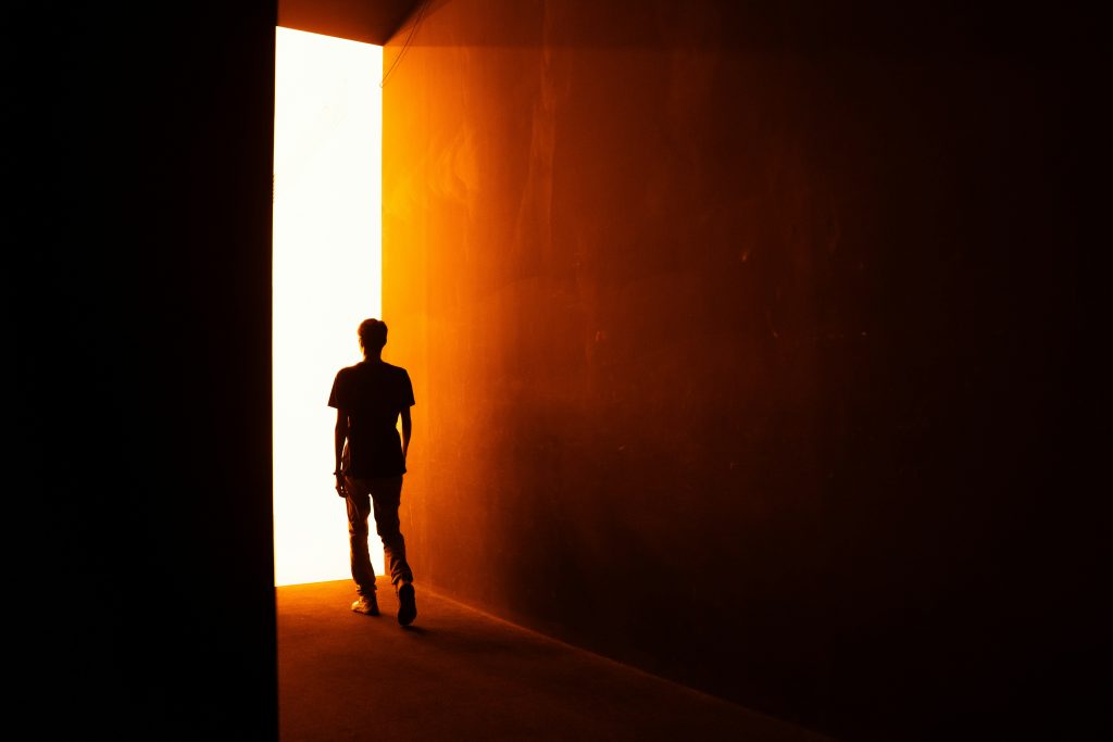 person walking toward light open door freedom
