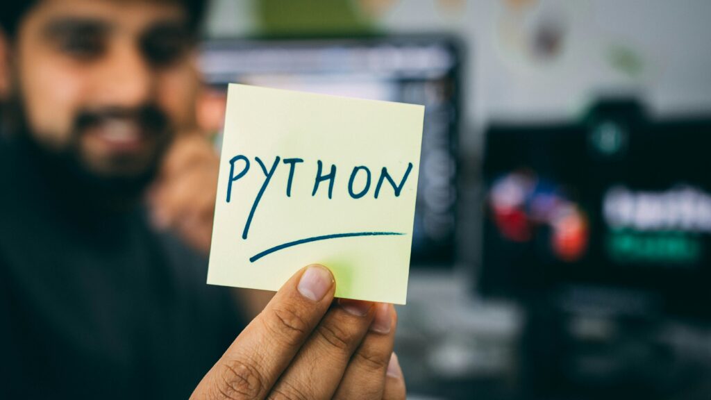 A young man is holding a piece of paper with the Python language logo.