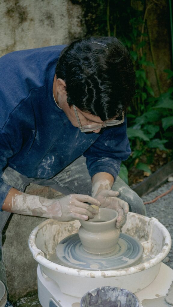 An artist creates a pottery vessel on a spinning wheel.
