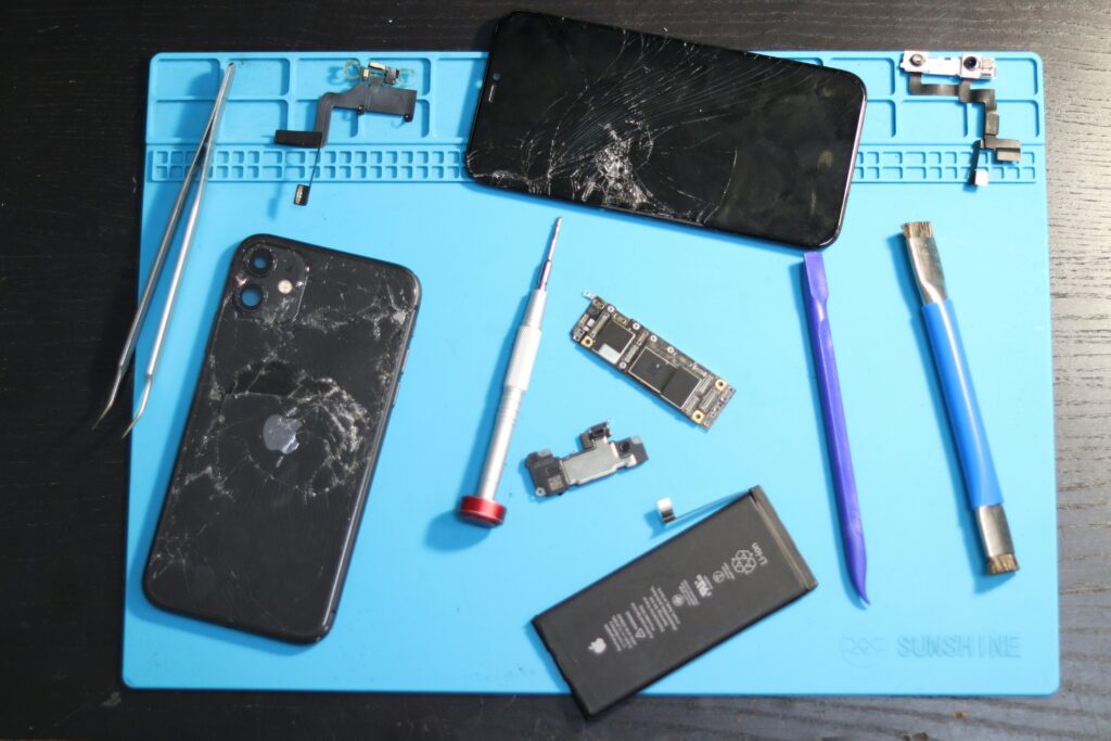 A mobile phone repair shop; tools and damaged phones are visible.